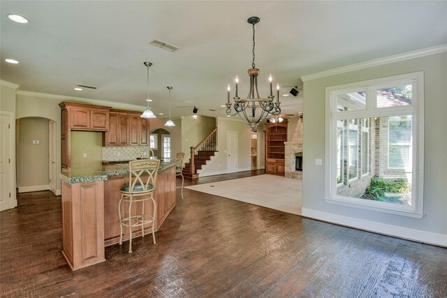 kitchen with a kitchen breakfast bar, a notable chandelier, backsplash, dark wood-type flooring, and a fireplace