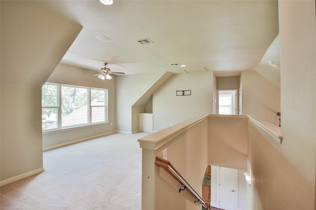 additional living space featuring a wealth of natural light, ceiling fan, vaulted ceiling, and light colored carpet