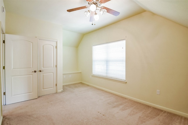 unfurnished bedroom with ceiling fan, a closet, lofted ceiling, and light carpet