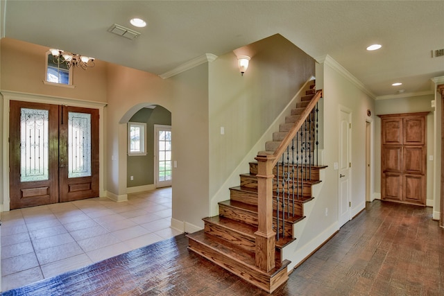 tiled entryway featuring an inviting chandelier, crown molding, and french doors