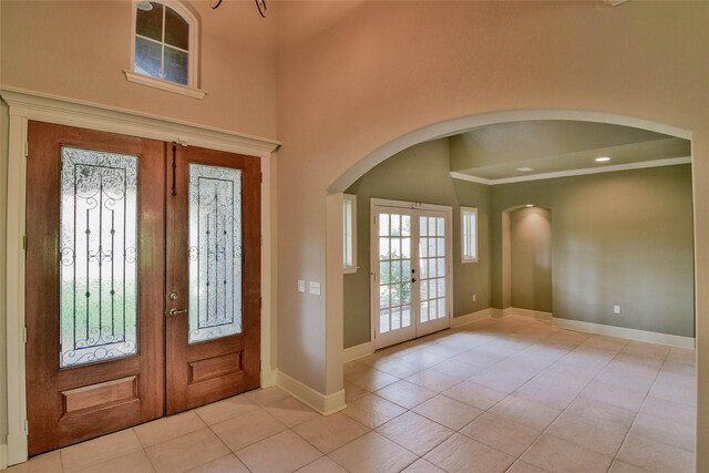 foyer with light tile patterned floors, a towering ceiling, and french doors