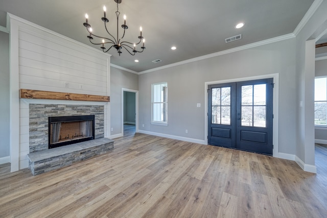 entryway featuring light wood-type flooring, crown molding, a notable chandelier, and a fireplace