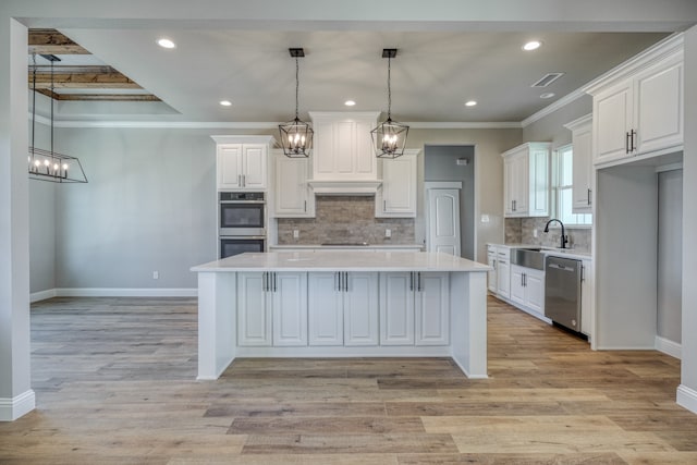 kitchen featuring appliances with stainless steel finishes, decorative backsplash, white cabinetry, light wood-type flooring, and a center island