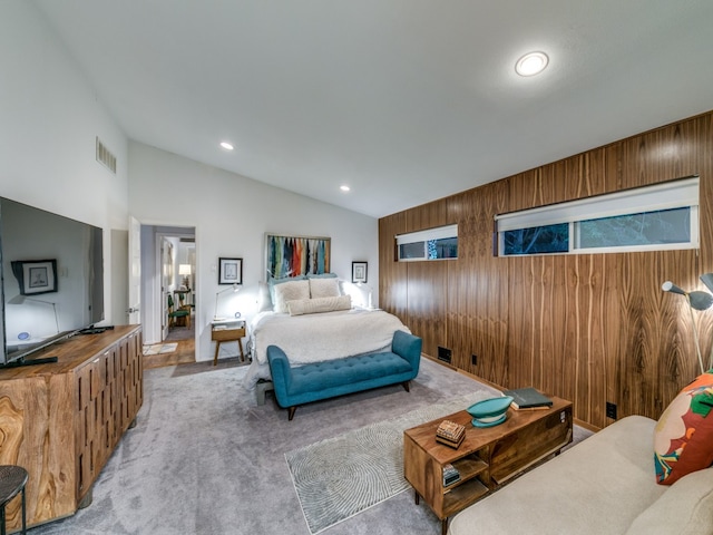 carpeted bedroom featuring vaulted ceiling and wood walls