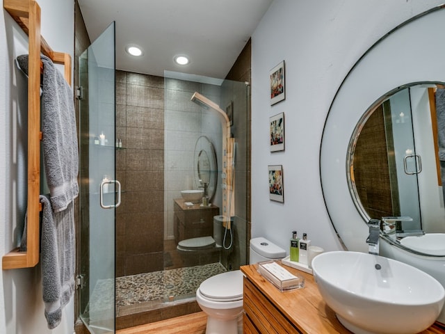 bathroom featuring vanity, toilet, wood-type flooring, and a shower with door