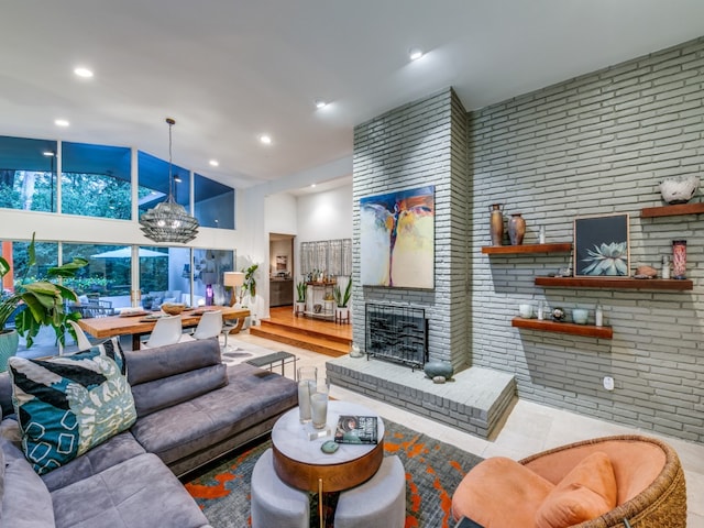 living room with brick wall, light hardwood / wood-style flooring, a chandelier, and a brick fireplace