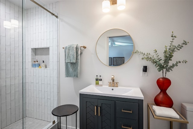 bathroom featuring toilet, a tile shower, and vanity