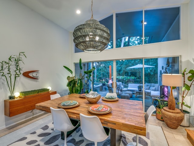 dining area featuring tile patterned floors, a notable chandelier, and high vaulted ceiling