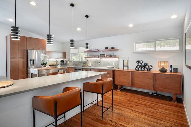 kitchen with a kitchen breakfast bar, dark hardwood / wood-style flooring, appliances with stainless steel finishes, sink, and lofted ceiling