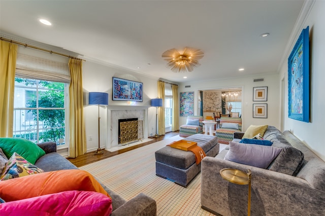 living room with light wood-type flooring, ornamental molding, and a high end fireplace