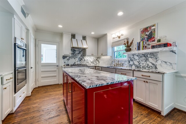 kitchen featuring sink, custom exhaust hood, dark hardwood / wood-style floors, appliances with stainless steel finishes, and white cabinetry