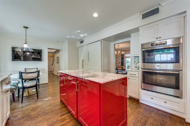 kitchen with light stone countertops, a center island, white cabinets, stainless steel double oven, and dark hardwood / wood-style flooring