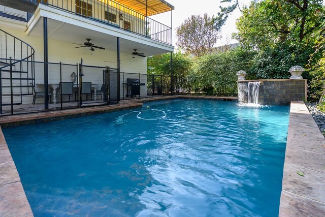 view of pool with ceiling fan, pool water feature, and grilling area