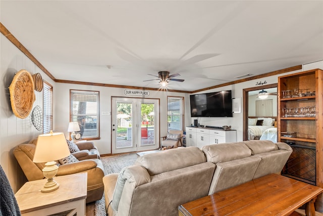 living room with ceiling fan, crown molding, and light wood-type flooring