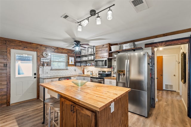 kitchen with light wood-type flooring, appliances with stainless steel finishes, butcher block counters, and a center island