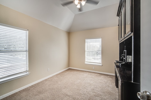 interior space with ceiling fan, vaulted ceiling, and light carpet