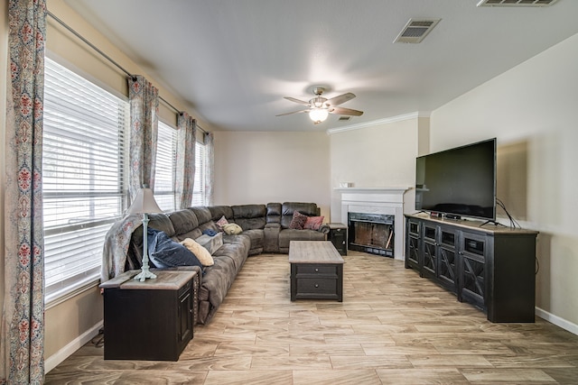 living room with ceiling fan, light wood-type flooring, a high end fireplace, and ornamental molding