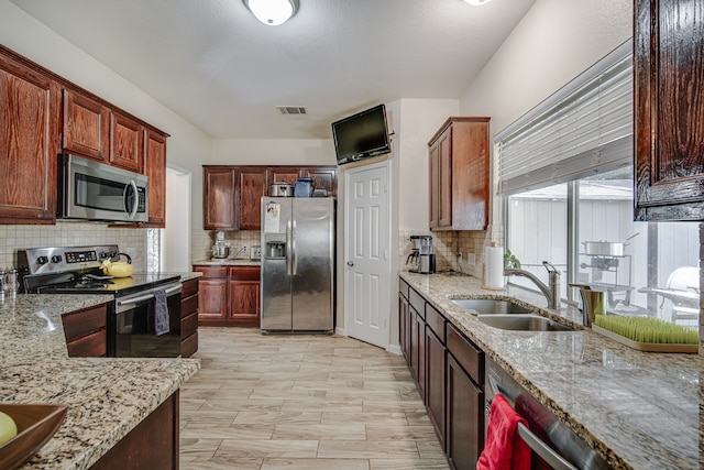 kitchen featuring backsplash, sink, stainless steel appliances, and light stone countertops