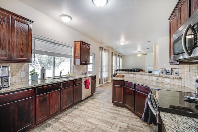 kitchen with appliances with stainless steel finishes, sink, tasteful backsplash, and light stone counters