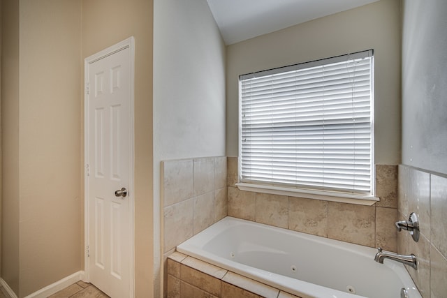 bathroom with tile patterned flooring and tiled tub