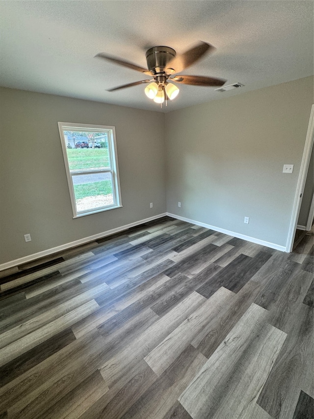 empty room featuring dark hardwood / wood-style flooring, ceiling fan, and a textured ceiling