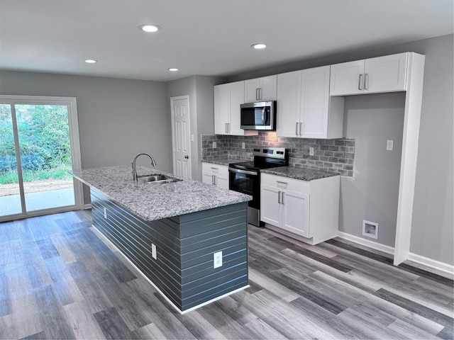 kitchen featuring an island with sink, stainless steel appliances, sink, white cabinetry, and light stone counters