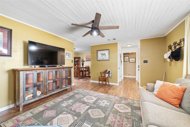 living room with crown molding, wood-type flooring, wooden ceiling, and ceiling fan