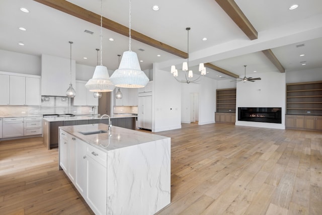 kitchen with white cabinets, decorative light fixtures, beam ceiling, and a spacious island