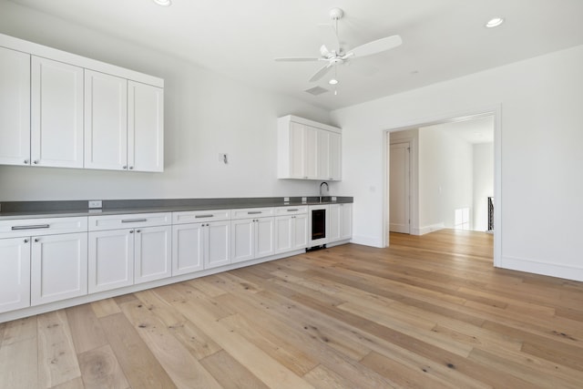 kitchen with wine cooler, light wood-type flooring, and white cabinetry