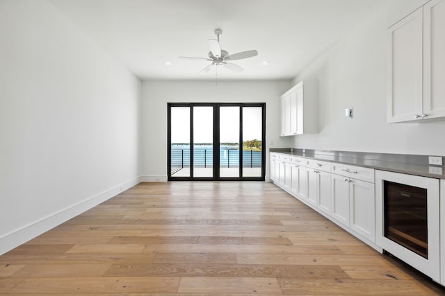 kitchen featuring white cabinets, ceiling fan, light wood-type flooring, and wine cooler