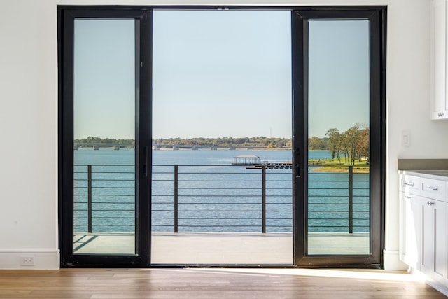 doorway to outside with light hardwood / wood-style floors and a water view