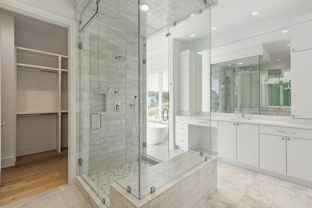 bathroom with vanity, wood-type flooring, and plus walk in shower