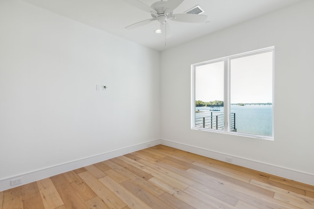 spare room with ceiling fan, a water view, and light hardwood / wood-style flooring