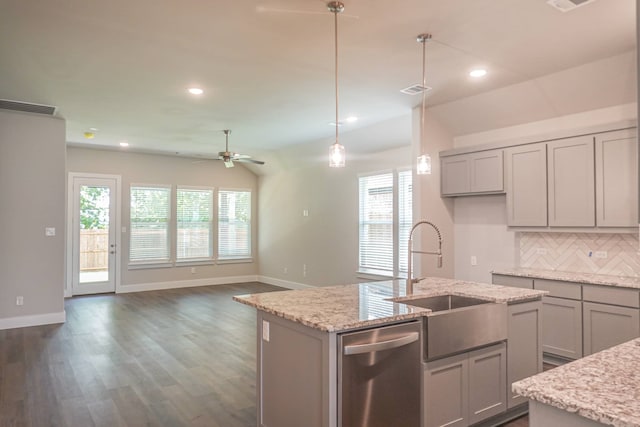 kitchen with sink, light stone counters, hanging light fixtures, dishwasher, and an island with sink