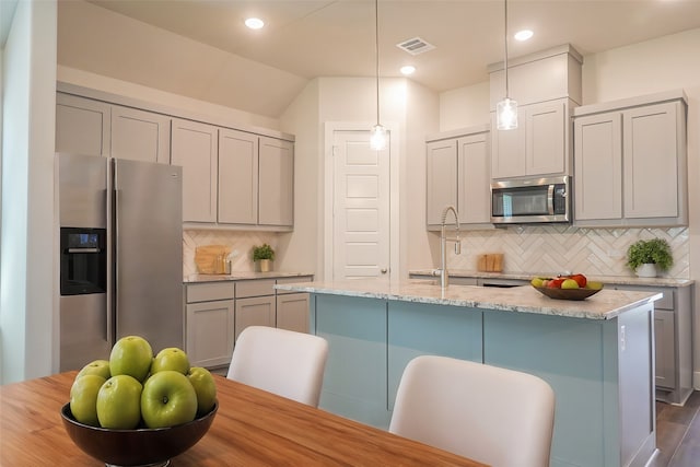 kitchen featuring pendant lighting, sink, light stone counters, an island with sink, and dark hardwood / wood-style flooring