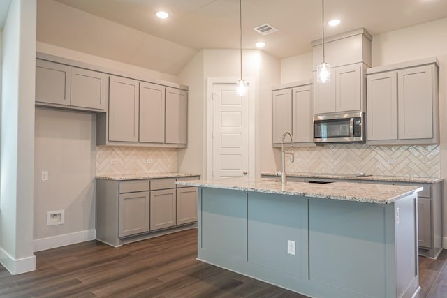 kitchen featuring stainless steel microwave, dark wood-type flooring, visible vents, and gray cabinetry