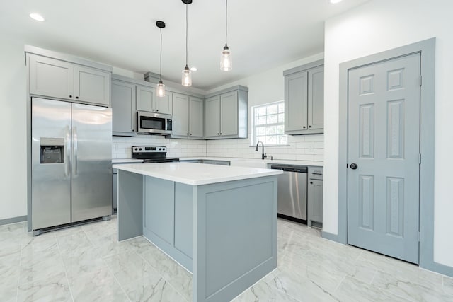 kitchen featuring gray cabinetry, a kitchen island, backsplash, stainless steel appliances, and hanging light fixtures