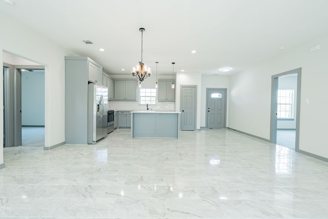 kitchen featuring an inviting chandelier, stainless steel fridge, gray cabinetry, pendant lighting, and a kitchen island