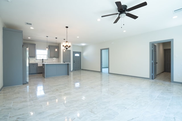 unfurnished living room featuring recessed lighting, visible vents, baseboards, and ceiling fan with notable chandelier