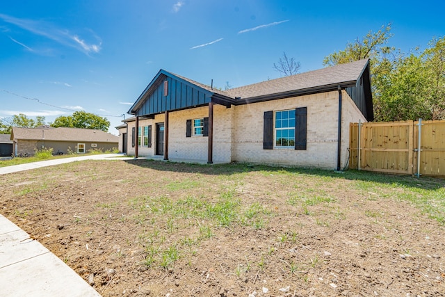 view of front facade with brick siding, fence, and board and batten siding