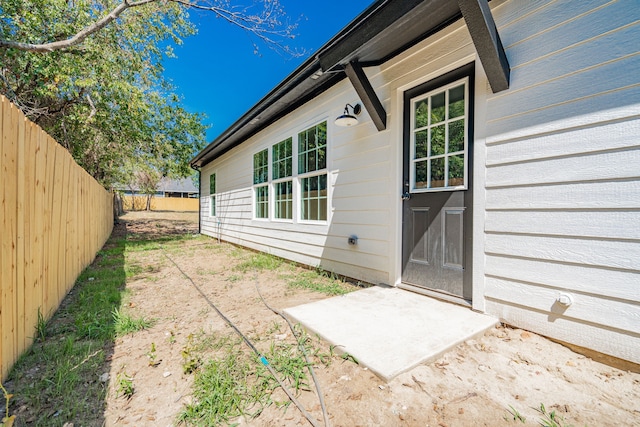 view of exterior entry with fence and a patio area