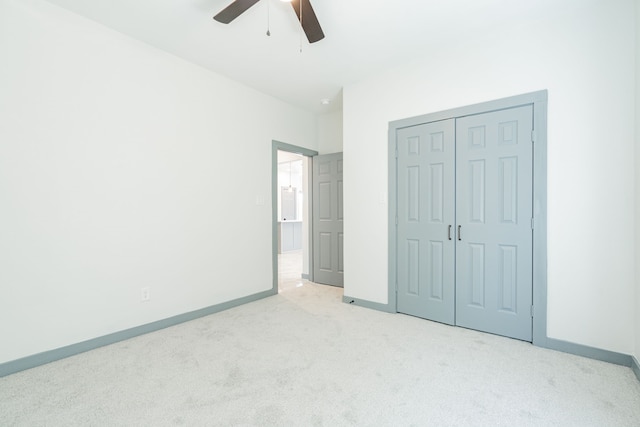 unfurnished bedroom featuring ceiling fan, a closet, baseboards, and light carpet