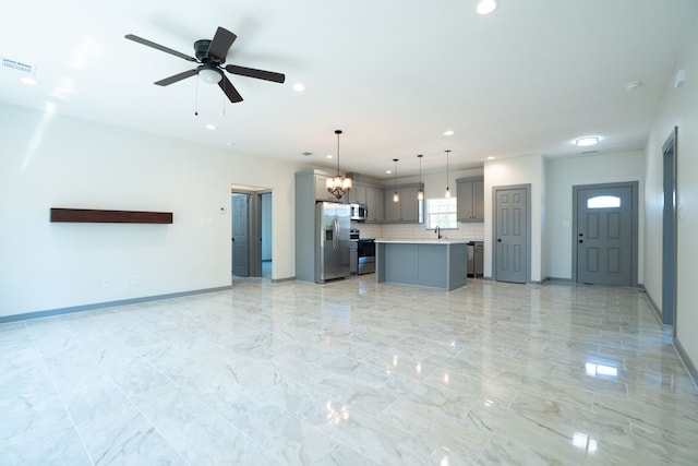 unfurnished living room featuring ceiling fan with notable chandelier and sink