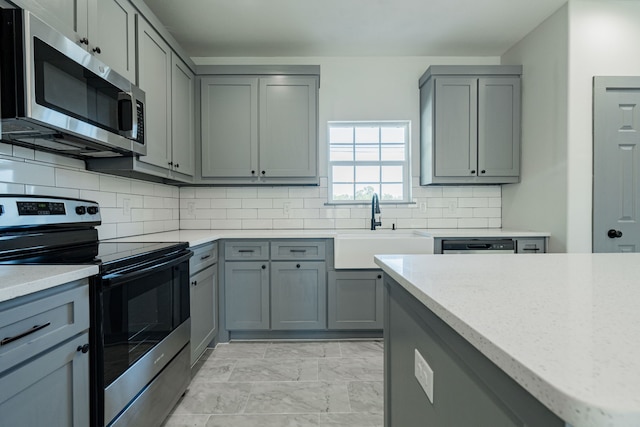 kitchen featuring gray cabinets, appliances with stainless steel finishes, sink, and decorative backsplash