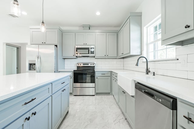 kitchen with stainless steel appliances, decorative light fixtures, sink, and light stone counters