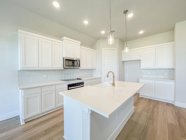 kitchen with sink, wall oven, an island with sink, light hardwood / wood-style flooring, and decorative backsplash