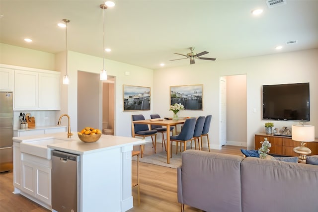 kitchen featuring stainless steel dishwasher, white cabinetry, pendant lighting, and light hardwood / wood-style flooring