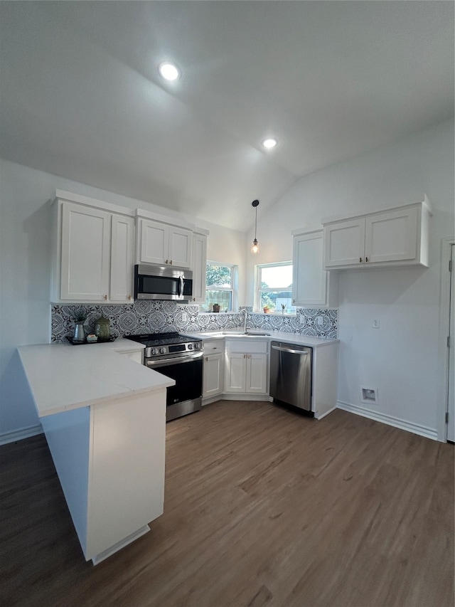 kitchen featuring white cabinets, lofted ceiling, decorative light fixtures, stainless steel appliances, and hardwood / wood-style floors