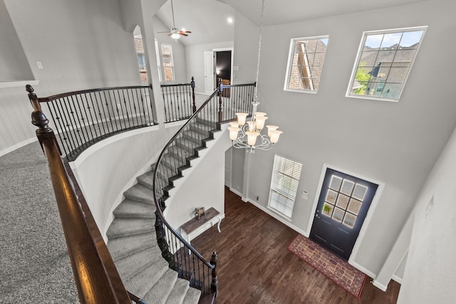 foyer with high vaulted ceiling, ceiling fan with notable chandelier, and dark hardwood / wood-style floors