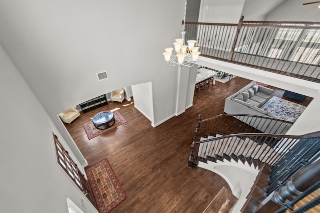 stairway featuring a towering ceiling, wood-type flooring, and a notable chandelier